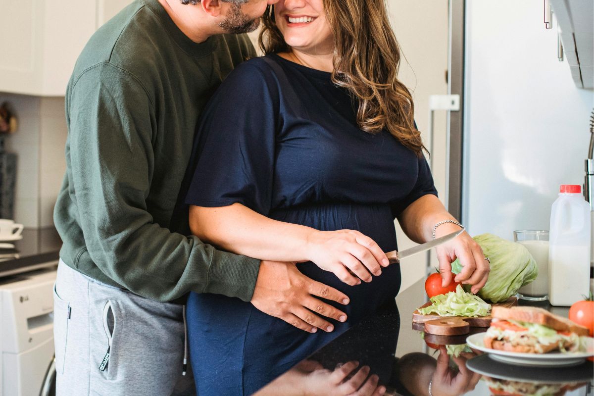Pregnant couple preparing a healthy meal together for a calm and supportive pregnancy routine.