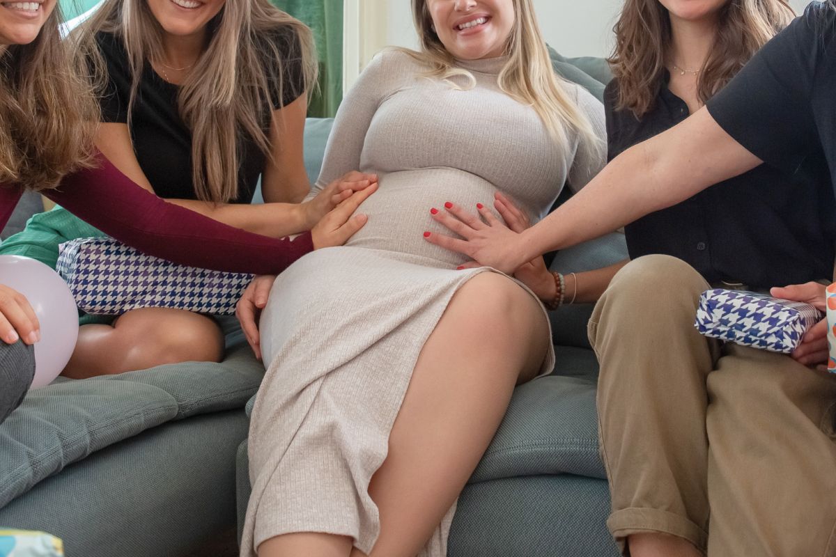 Pregnant woman surrounded by friends during a baby shower for emotional support during pregnancy.