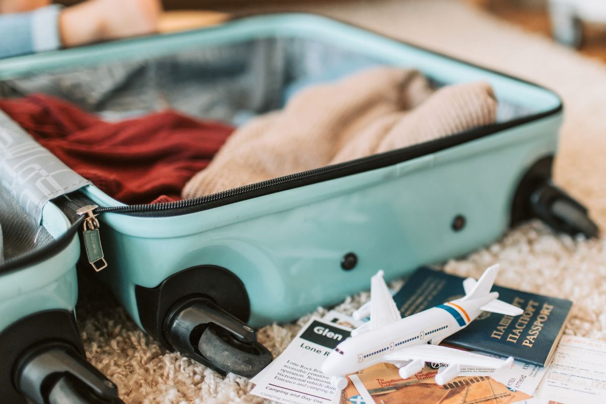 Packed suitcase with clothes and travel essentials for beach vacation with toddlers.