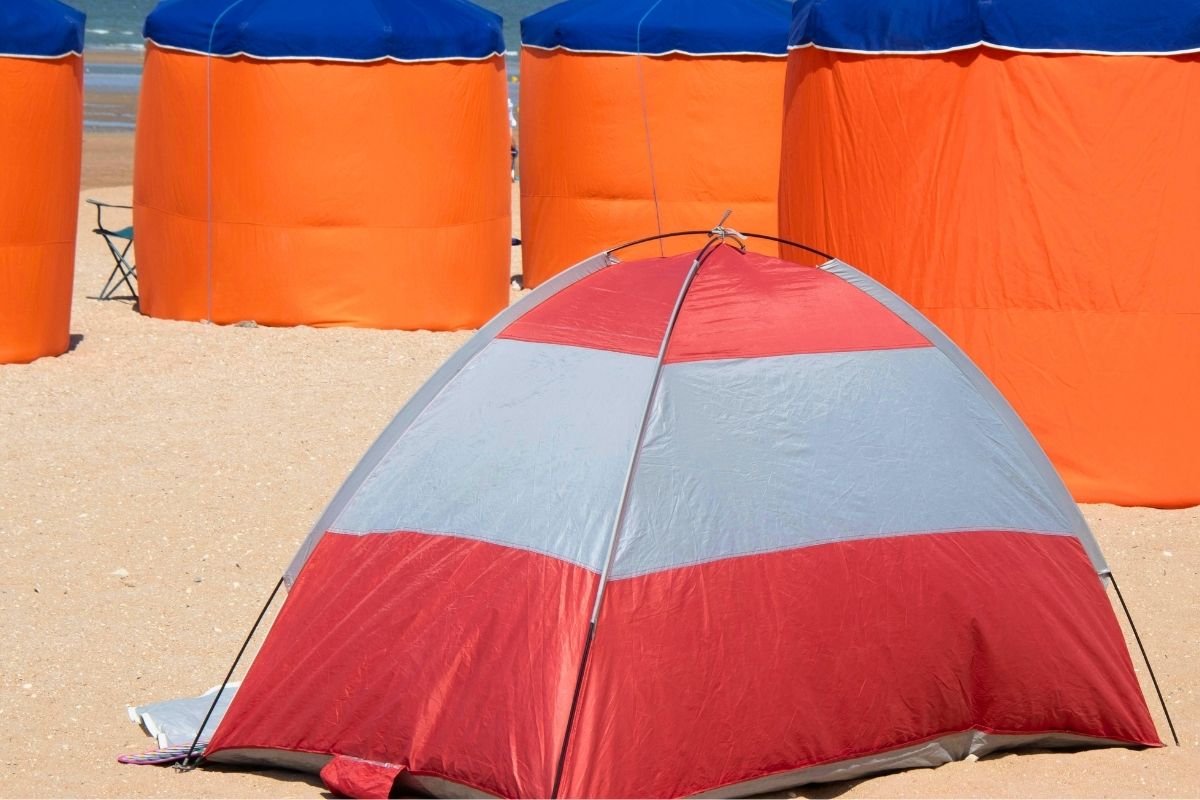 Beach tent set up on sand for shade and sun protection in toddler beach vacation packing list.