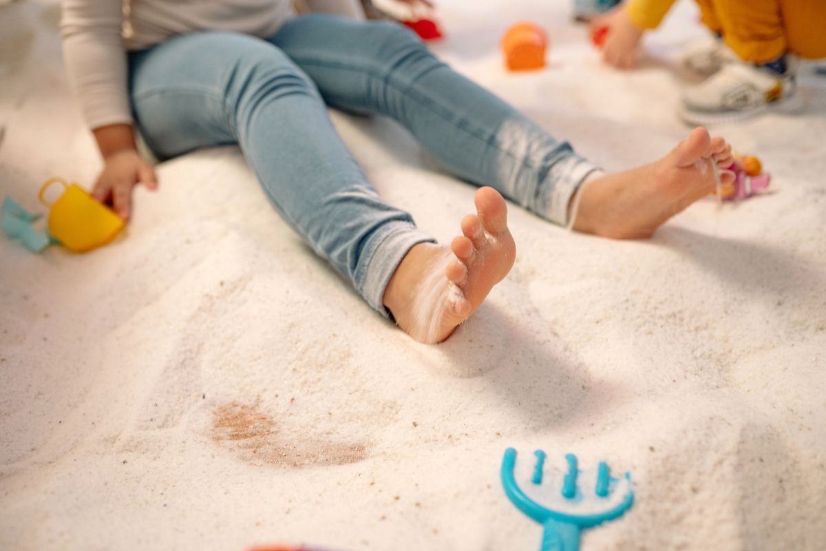 Sandy toddler feet after play highlighting need for cleanup items in beach vacation packing list for toddlers.