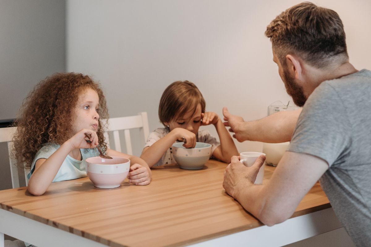 Parent guiding children during mealtime with calm and clear boundaries.