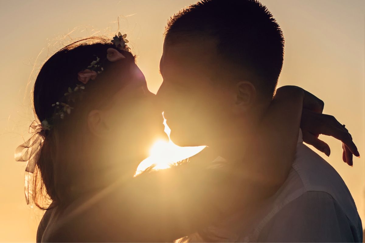 Expecting couple sharing a romantic sunset kiss, capturing a sweet pregnancy memory before becoming parents.