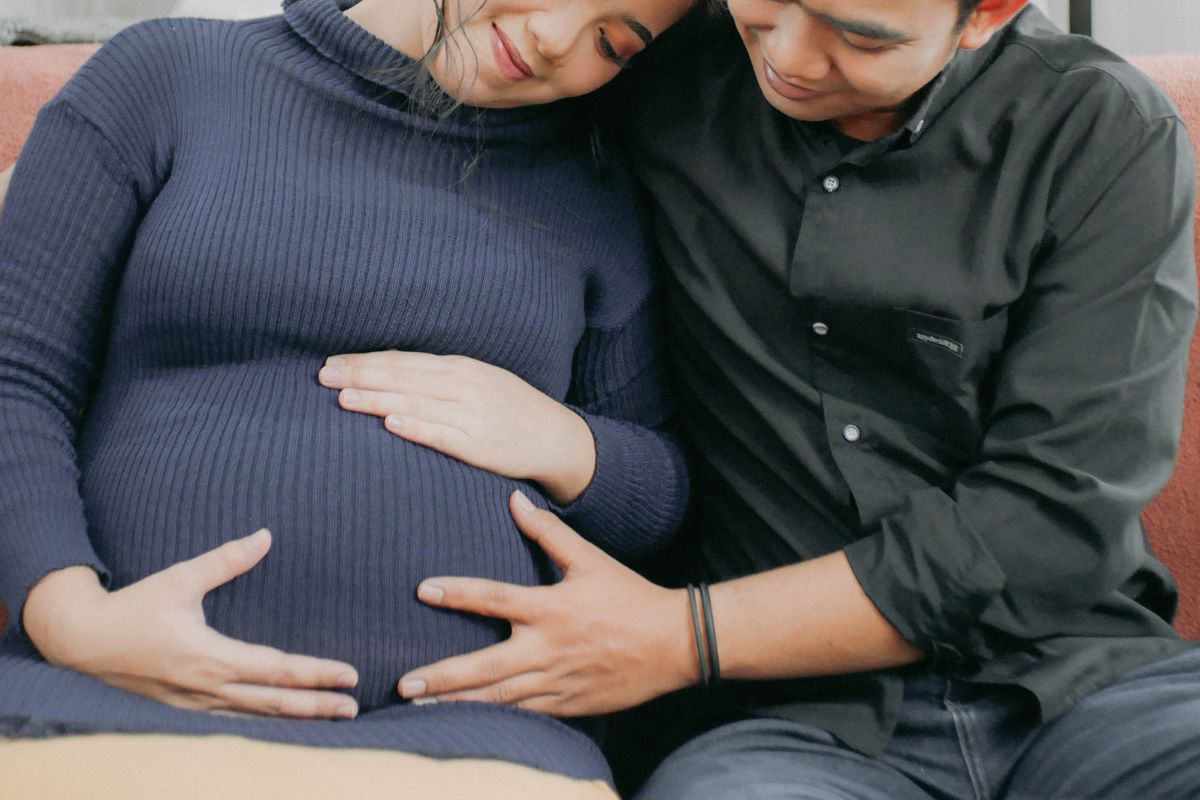 Pregnant woman and partner relaxing together on the couch, a cozy at home date night idea during pregnancy.