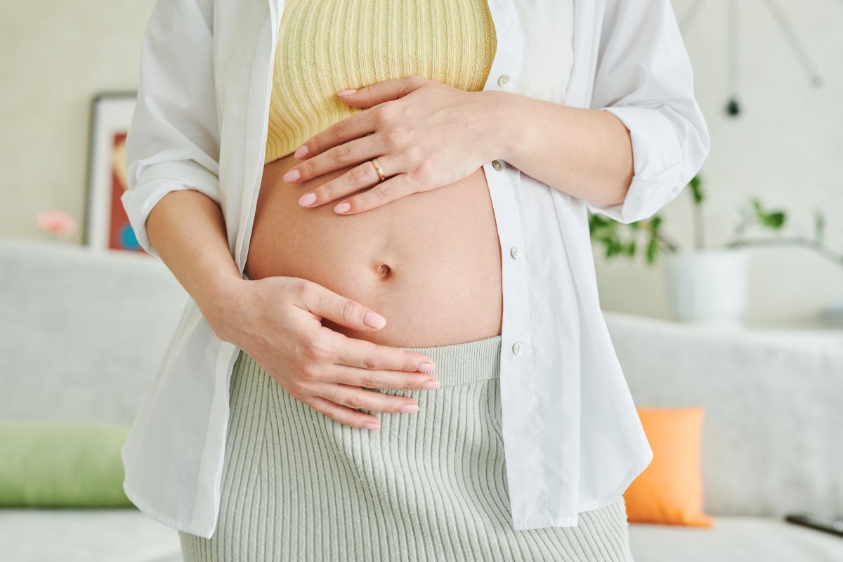 Pregnant woman holding baby bump while preparing for motherhood and postpartum recovery.