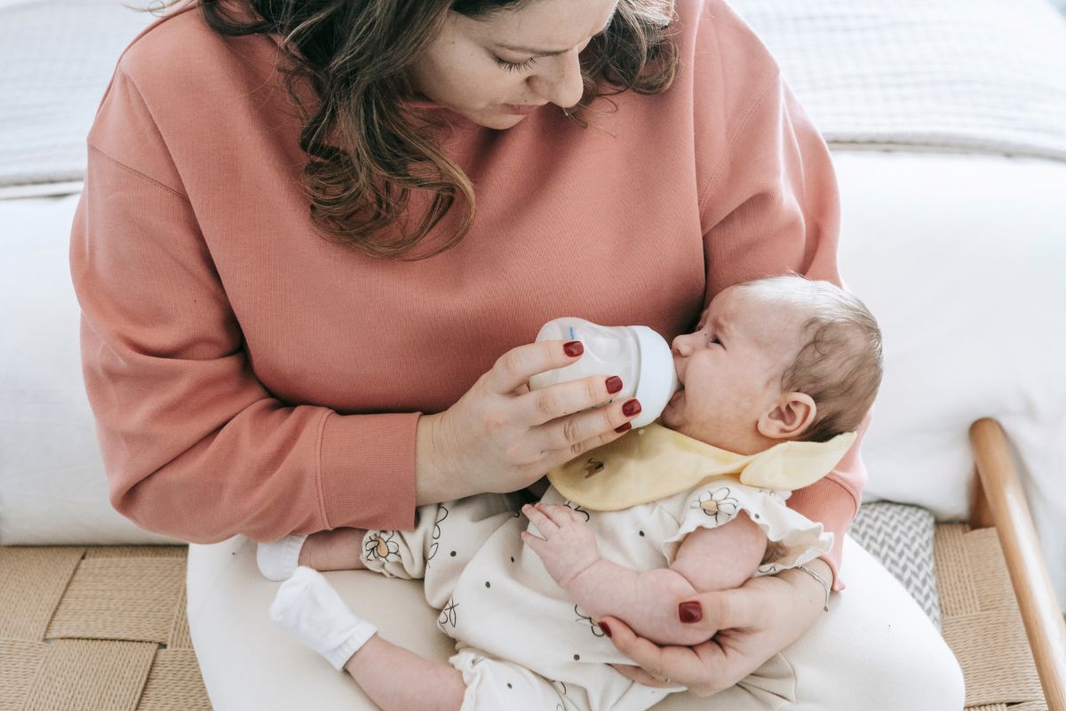 Mother bottle-feeding her baby while establishing a feeding routine before returning to work.