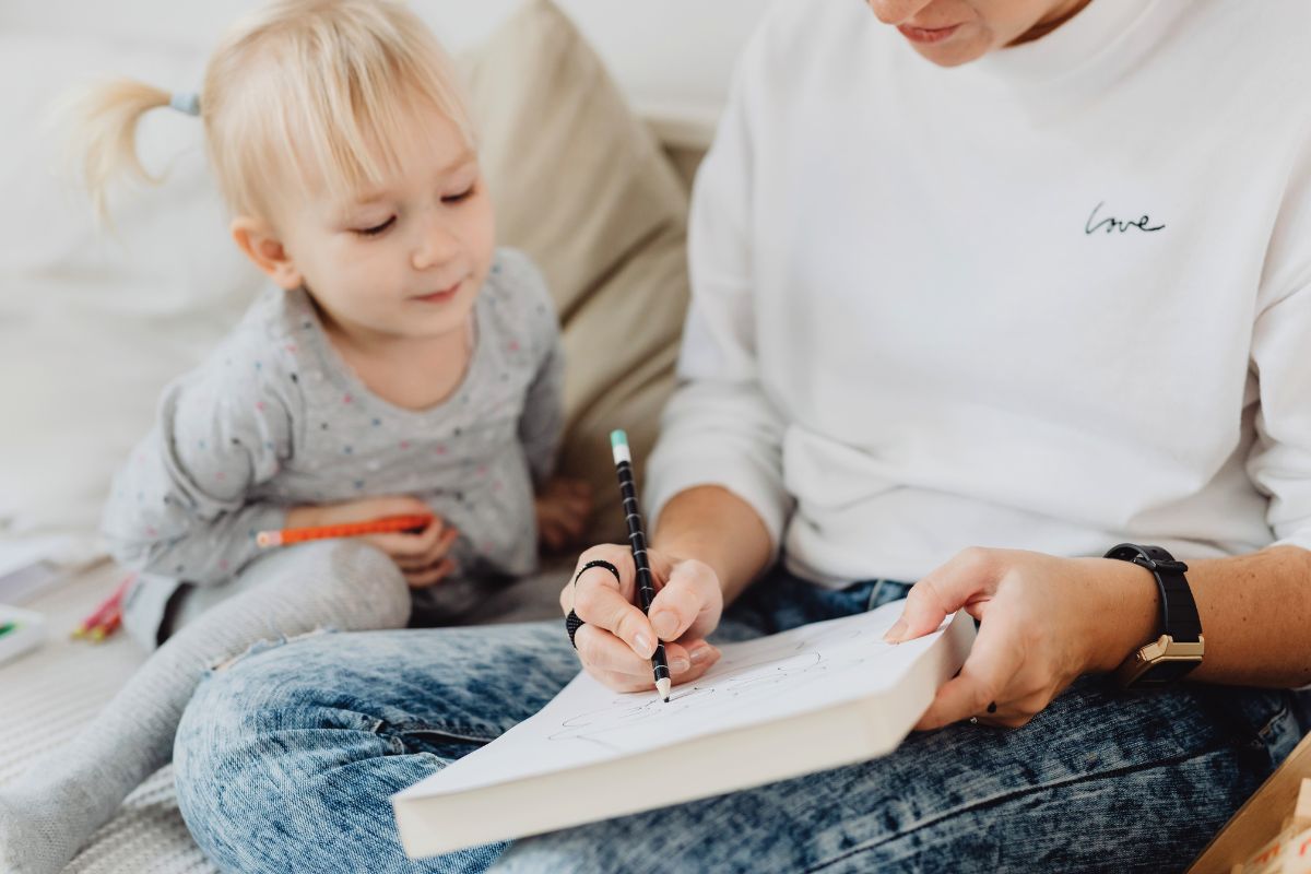 Mother writing a returning-to-work checklist while sitting beside her young child.