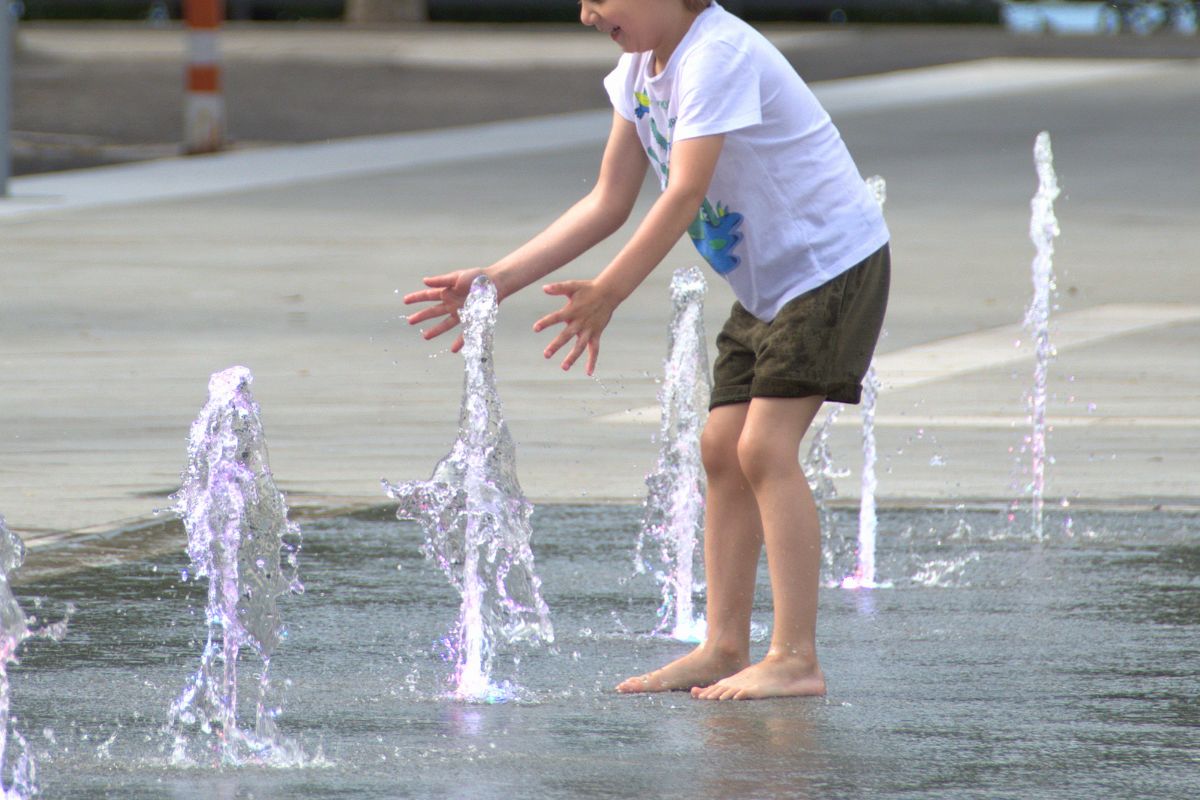 Child playing in water fountains during a summer staycation activity for kids.