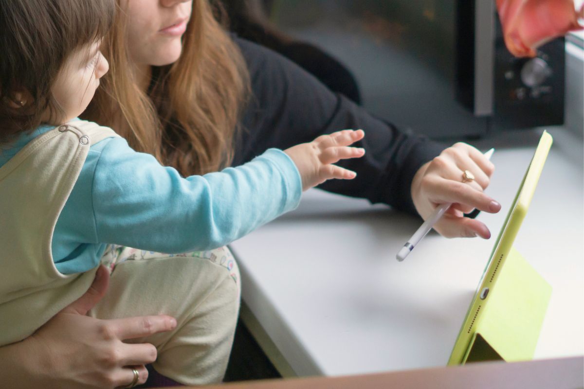Parent using ChatGPT prompts for parents on a tablet while helping a young child learn at home.