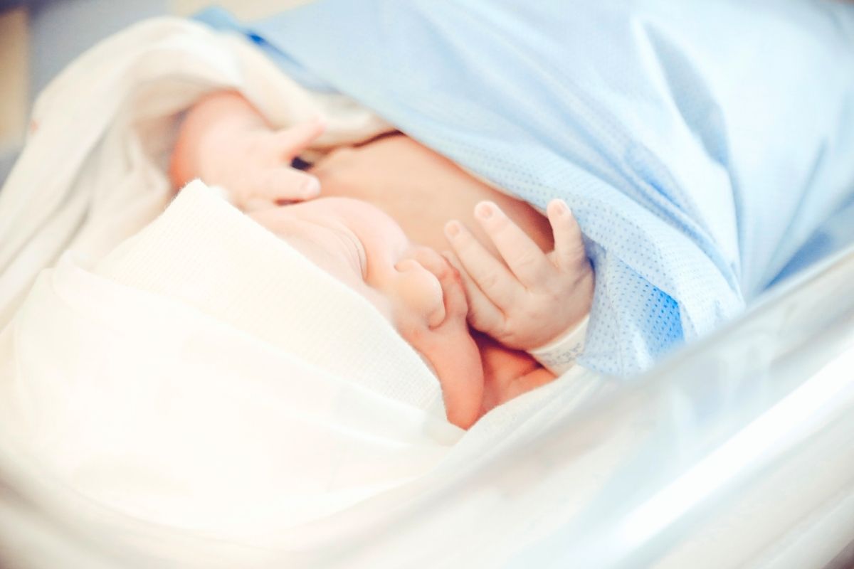 Newborn baby wrapped in a blue blanket, resting in a hospital bassinet.