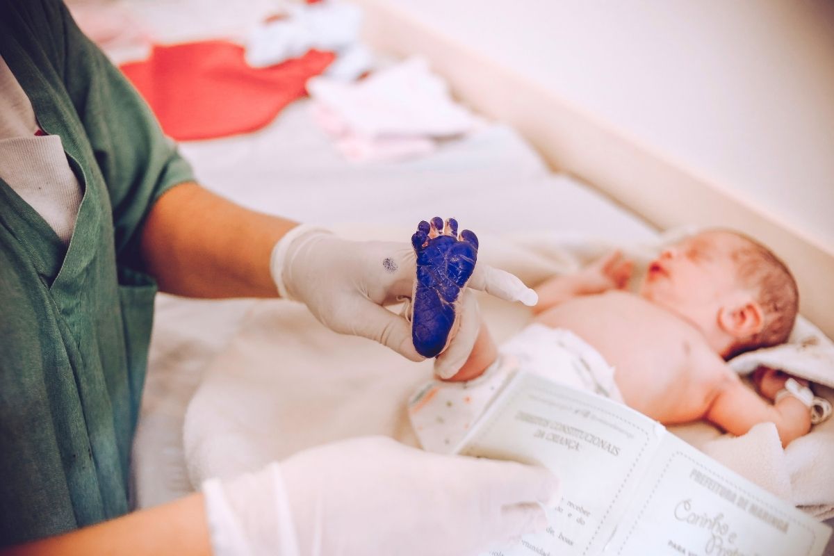 Hospital staff holding a newborn baby’s foot while taking a footprint.