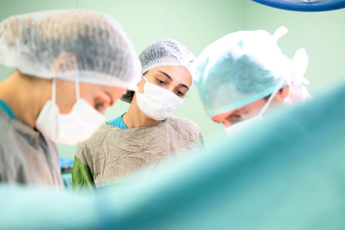 Medical staff wearing surgical masks and caps in an operating room.