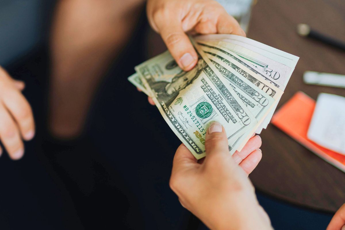 Hands exchanging cash during a budgeting or expense tracking conversation at home.
