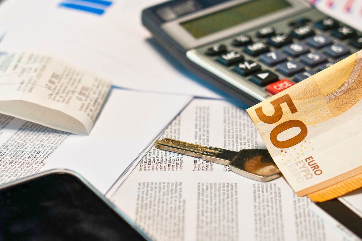 Calculator, receipts, and cash on a desk while organizing household expenses and budgeting finances.