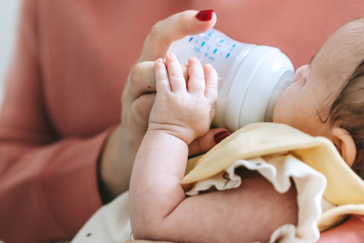 Baby being bottle-fed while lying down, showing a feeding essential for a travel-friendly baby packing list.