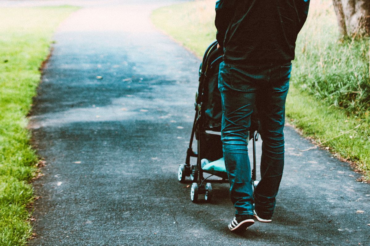 Parent pushing a stroller on a path, representing on-the-go essentials for a travel-friendly baby packing list.