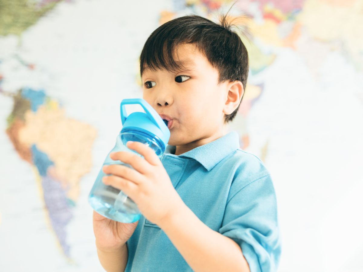 Toddler drinking from a leak-proof, colorful water bottle.