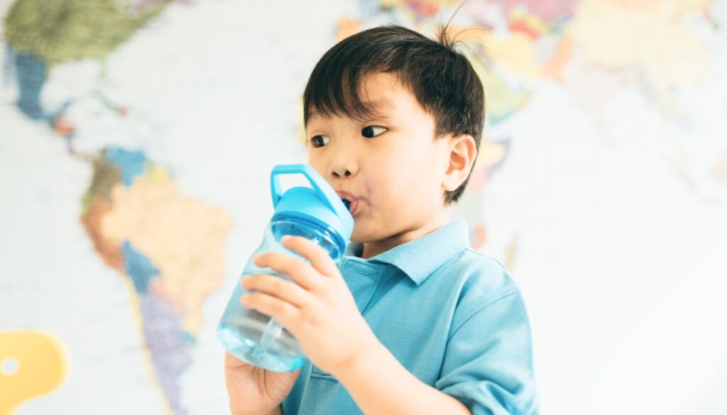 Toddler drinking from a leak-proof, colorful water bottle.