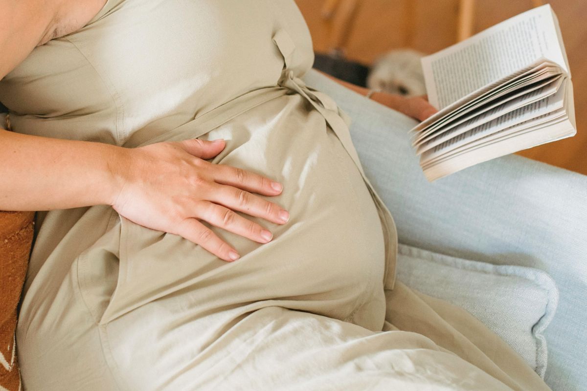 Pregnant woman relaxing with a book while preparing for a calm babymoon before baby arrives.