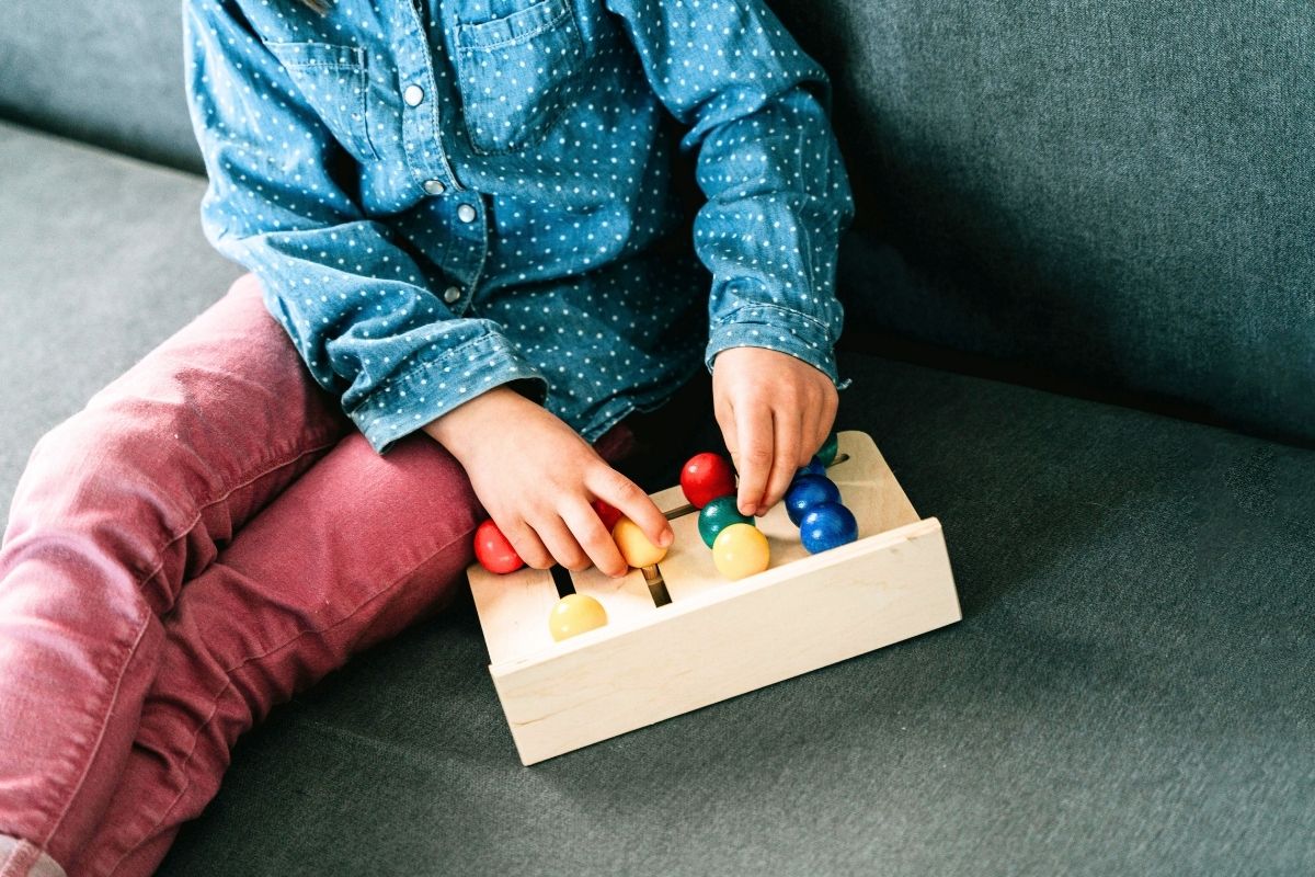 Toddler playing with a wooden toy puzzle indoors.