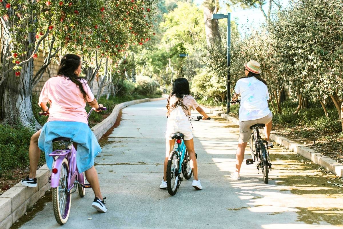 Kids riding bicycles together on a quiet tree-lined road.