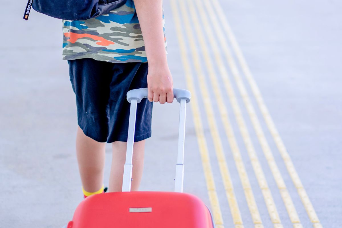 Child pulling suitcase at airport, what to pack in a kids carry on.