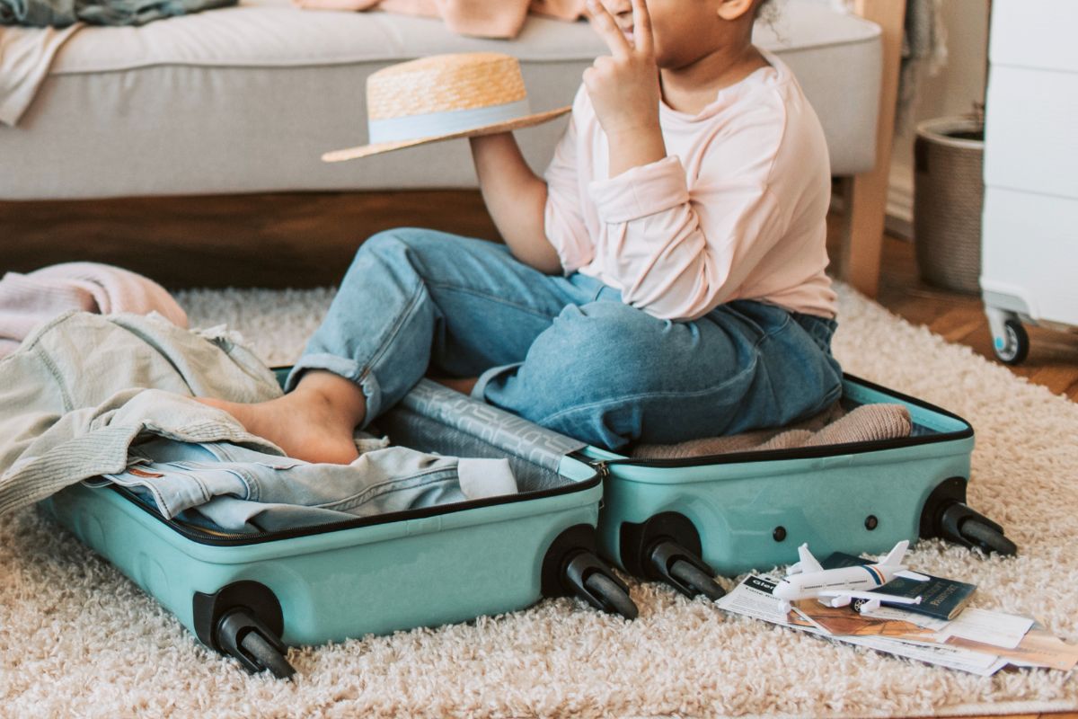 Child packing suitcase at home, what to pack in a kids carry on list.