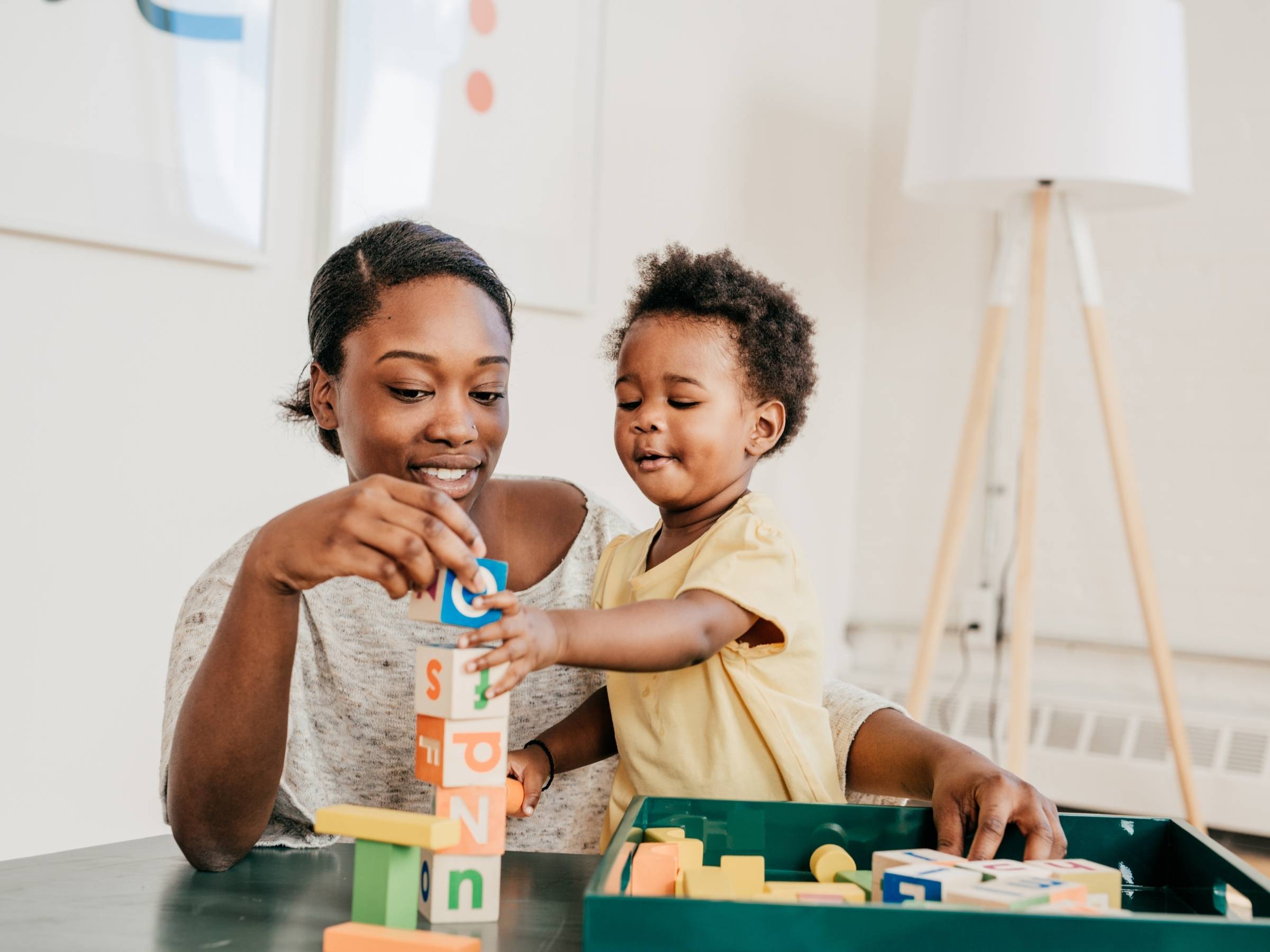 mother and boy toddler stacking colorful building blocks at a table