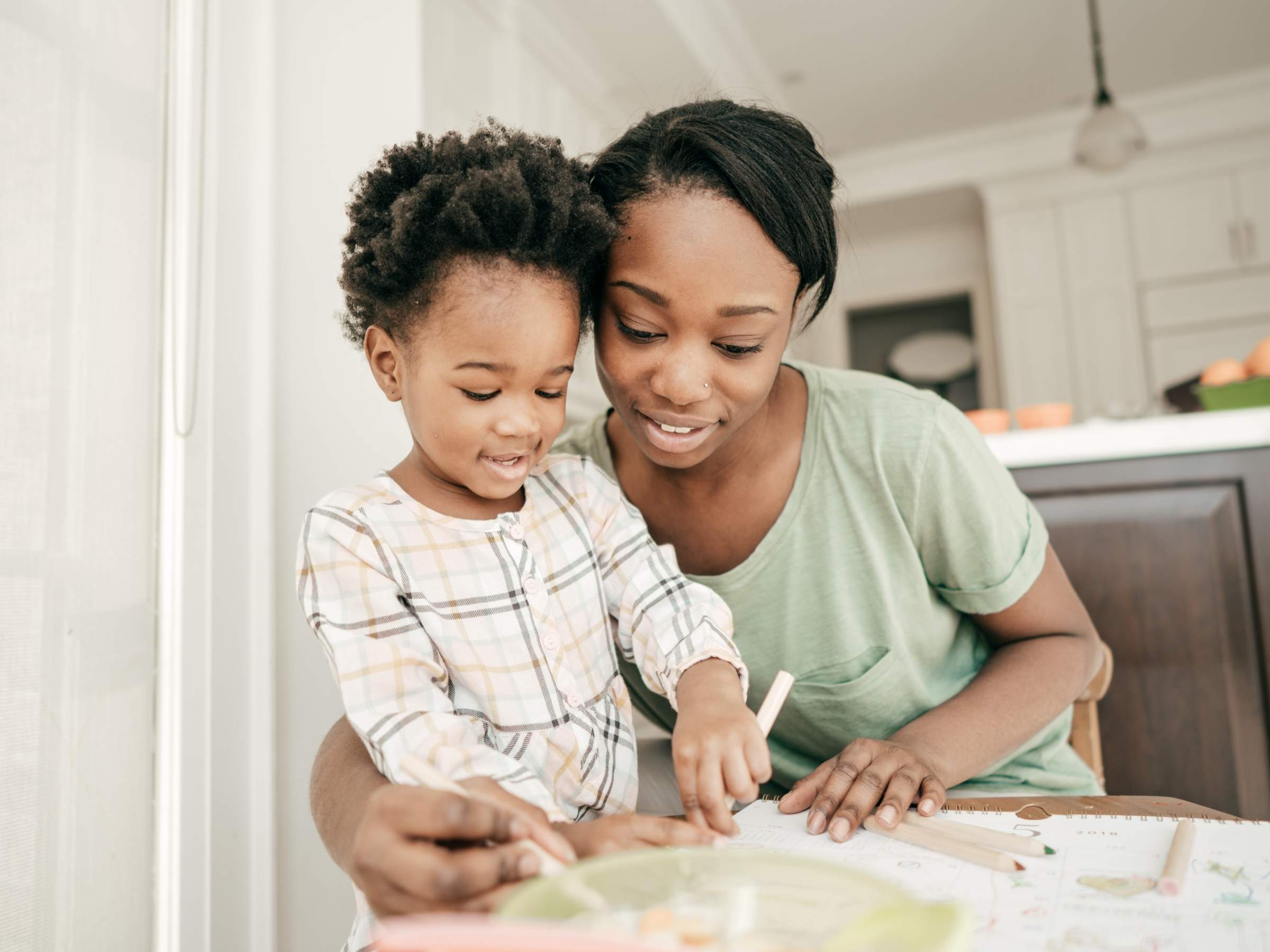 mother and boy toddler engaged in drawing or writing activities.