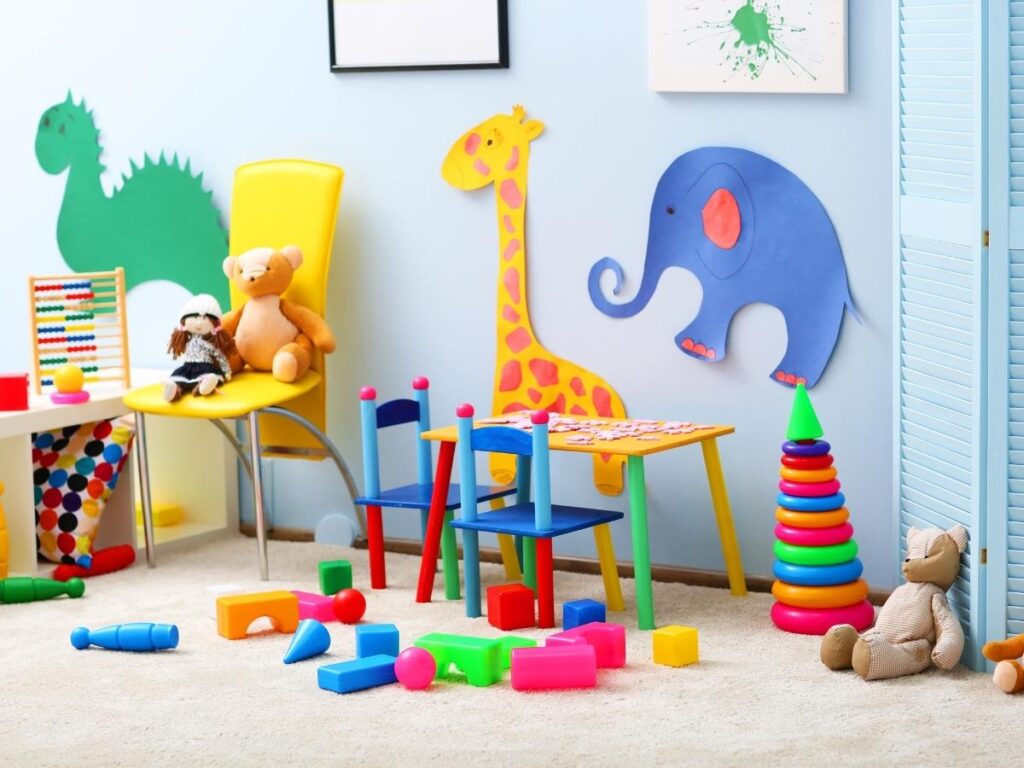Colorful children's playroom with toys, building blocks, a teady bear, an abacus, and toddler furnitures, and some animal cutouts on the blue wall