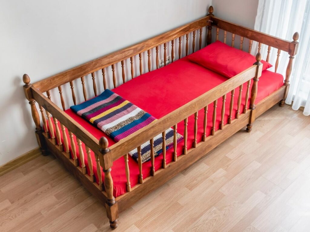 Wooden toddler's bed with red mattress and pillow