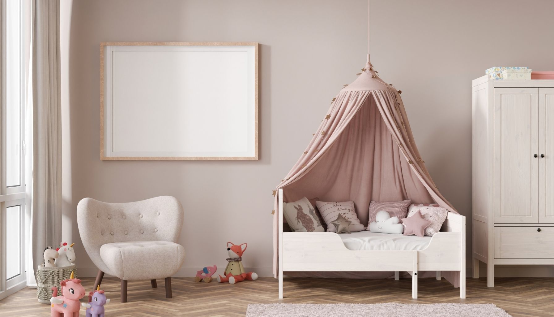 A cozy toddler bedroom featuring a white toddler bed with a pink canopy, soft pillows, stuffed animals, a small armchair, and a white wardrobe.