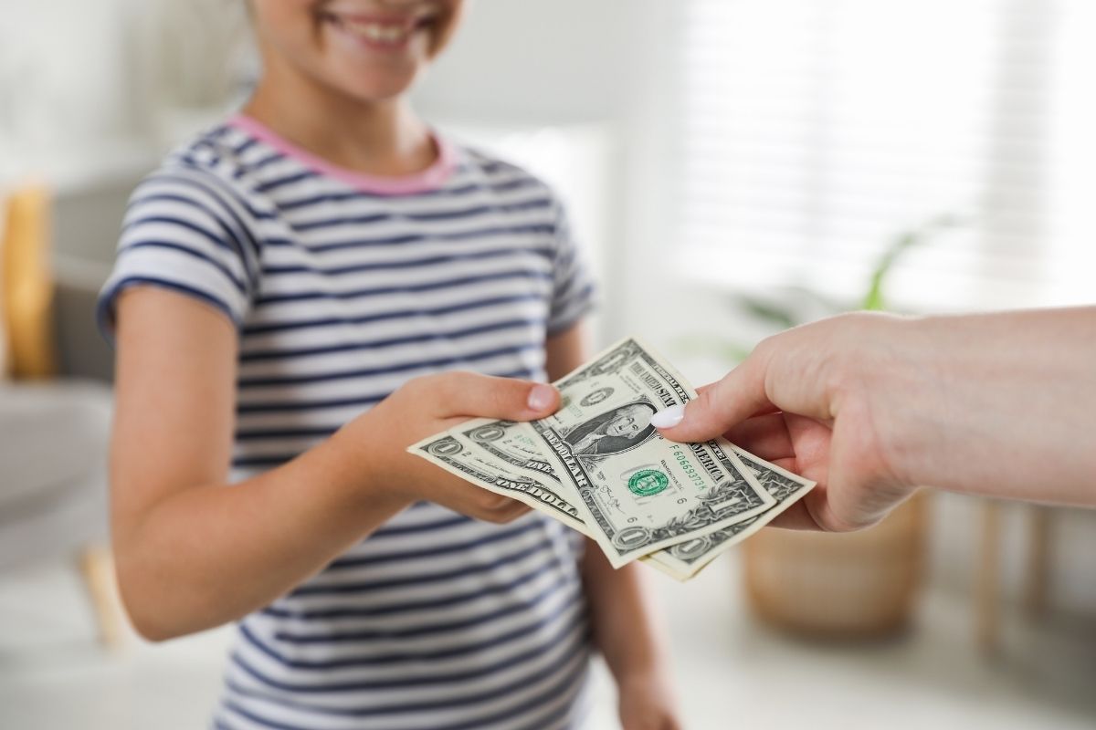 Child receiving cash from an adult as part of an allowance.
