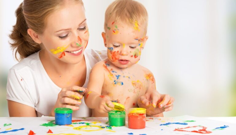 mother and toddler engaged in a painting activity at a white table