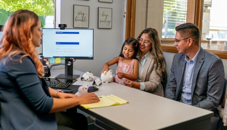 Parents with their young daughter meeting with a bank representative at a desk with piggy banks