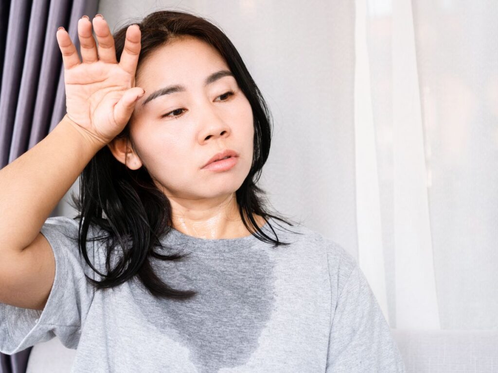 Mother in a sweat-soaked gray shirt wiping forehead