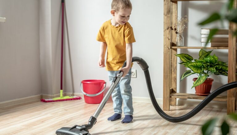 Young boy vacuuming the floor at home as part of his household chores.