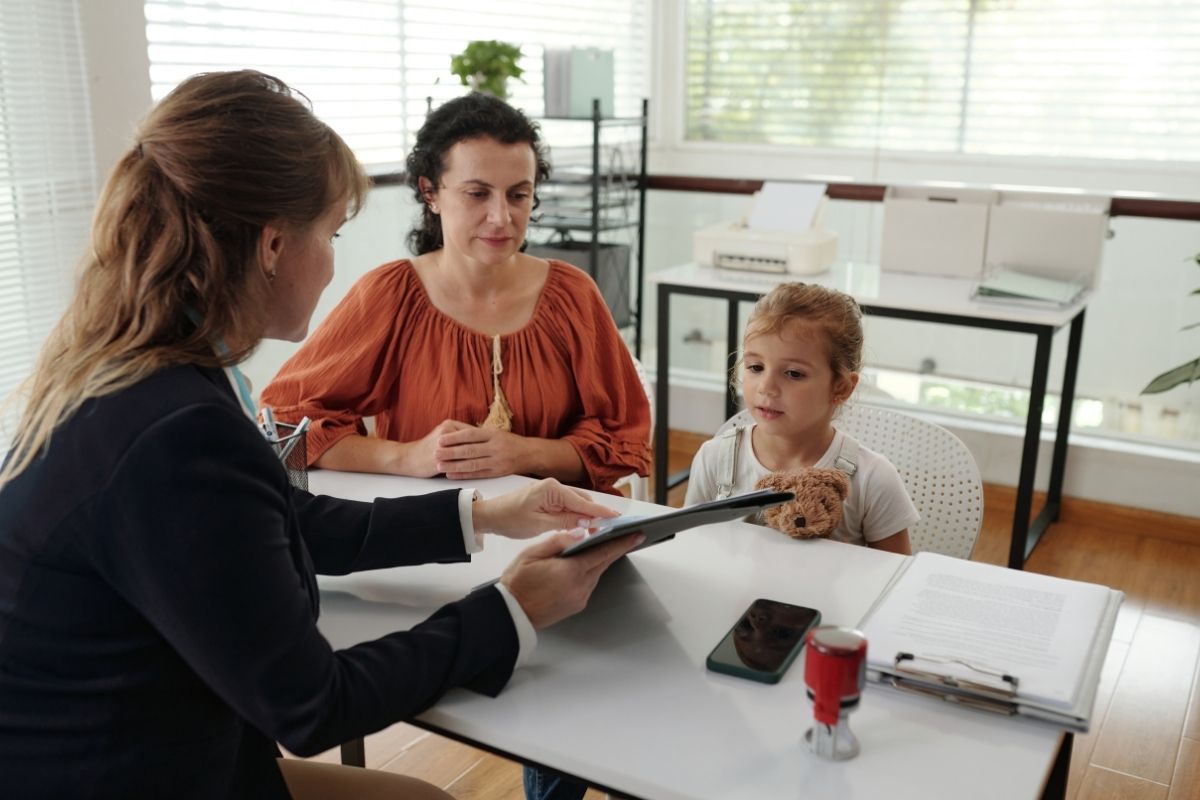 Parent and child meeting with a bank representative to discuss opening a bank account.