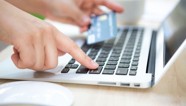 Hands using a laptop while holding a bank card during an online banking setup.