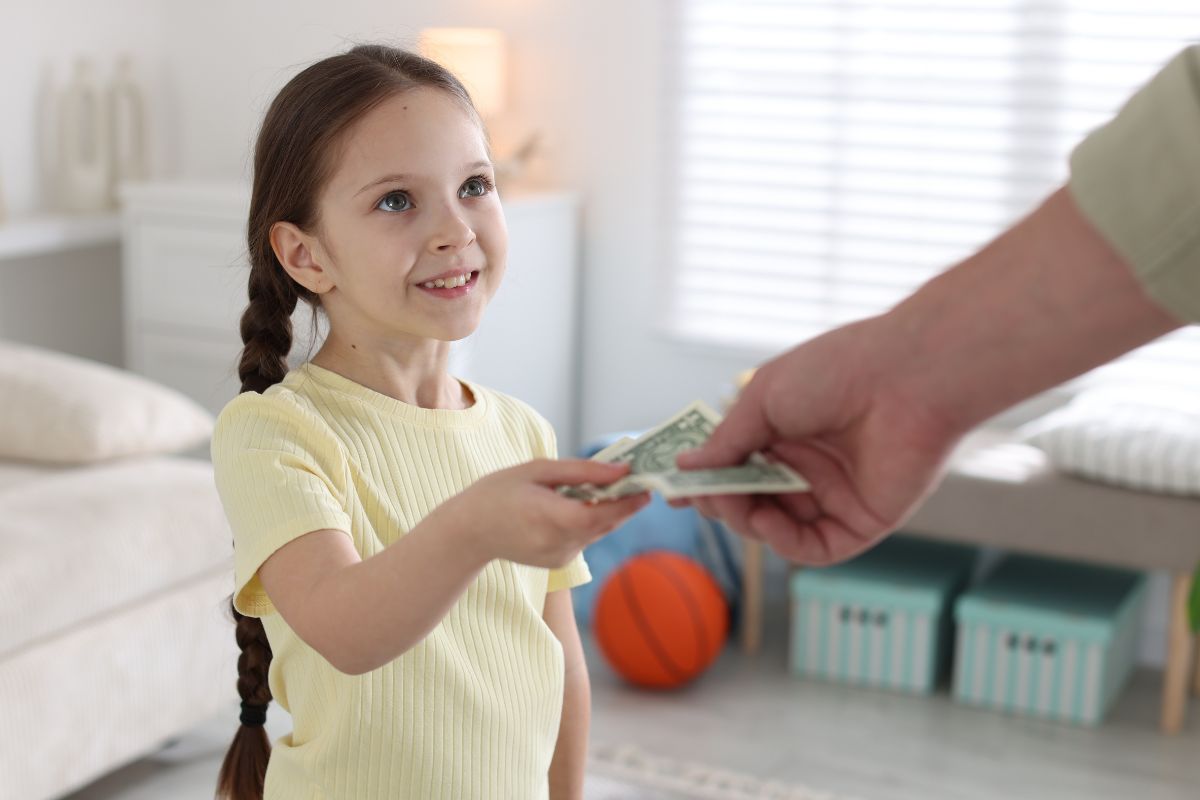 Young girl giving cash to an adult.