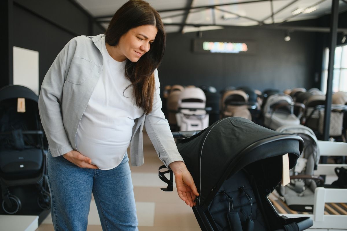 Pregnant woman comparing strollers while shopping in a baby store.