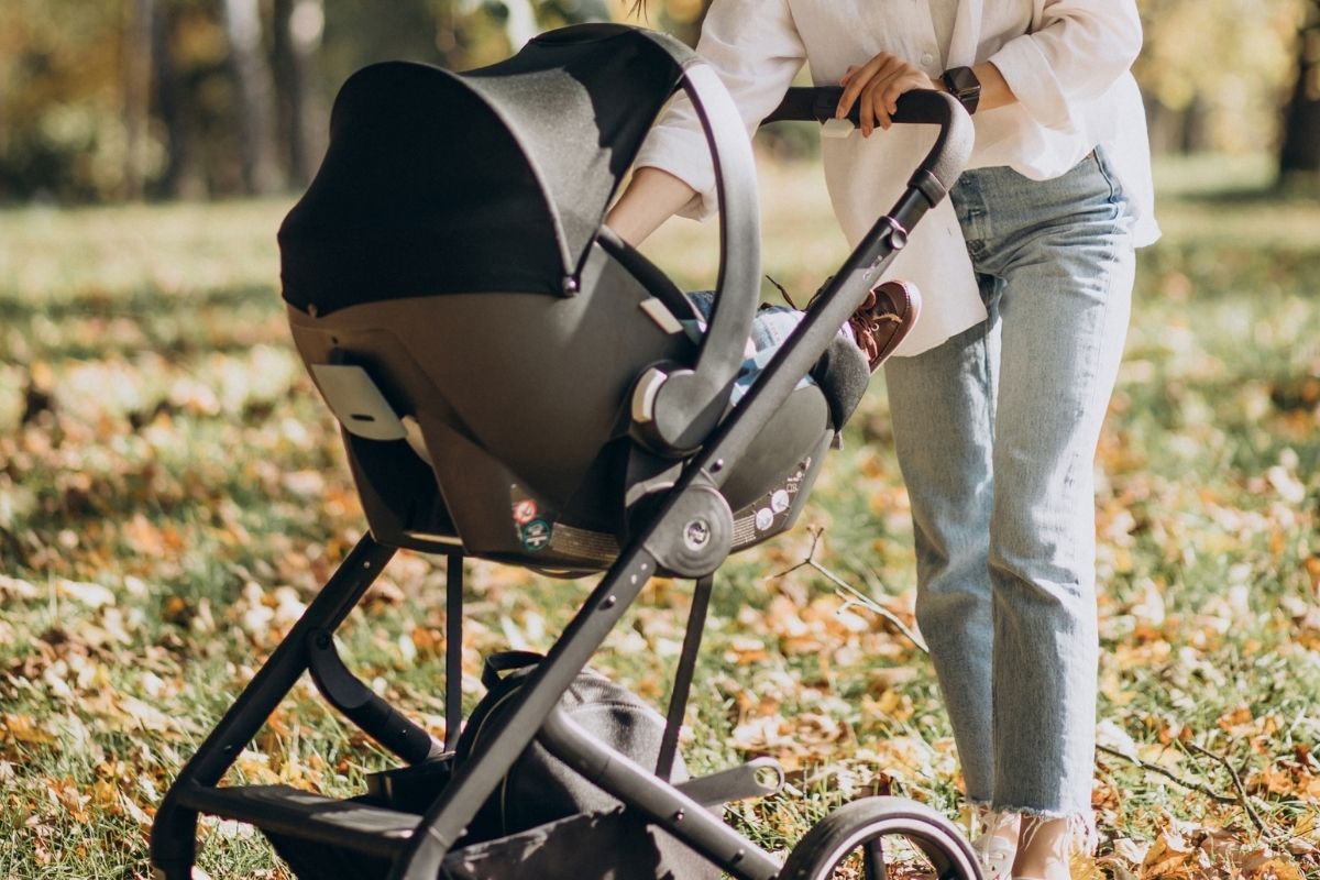 Baby travel system with an infant car seat attached to a stroller frame outdoors.