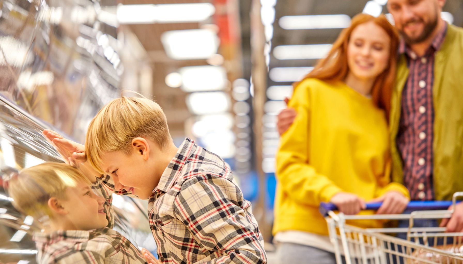 Young boy choosing an item from a store shelf while shopping with his parents.
