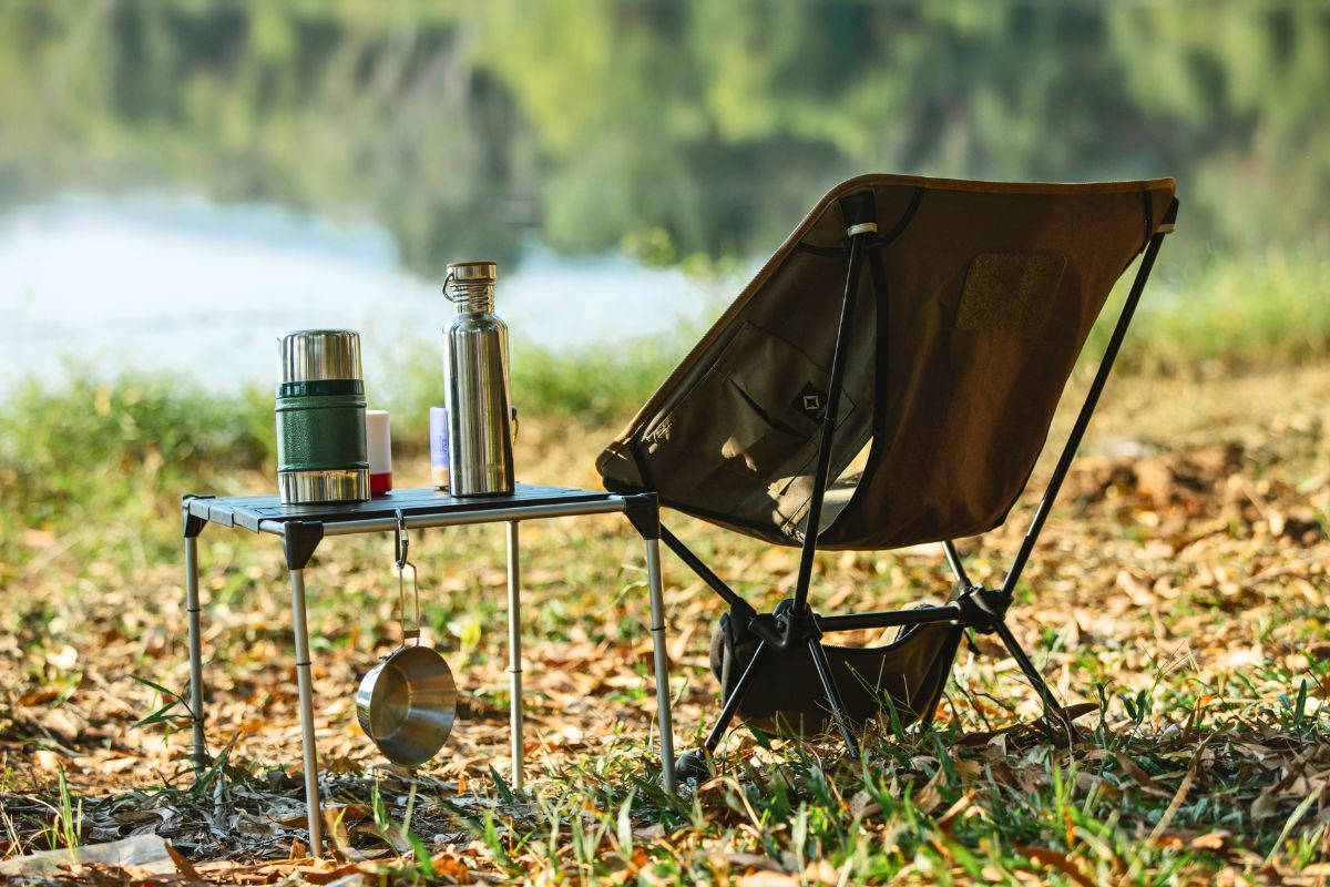 Camping essentials setup with chair and gear near a lake for a relaxing family camping trip with kids.