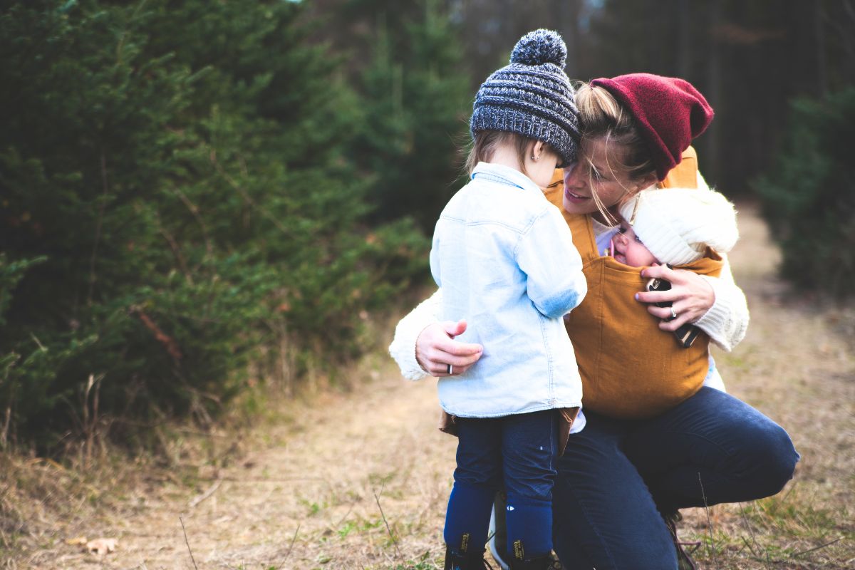 Mom with two kids enjoying outdoor time during a family camping trip in nature.
