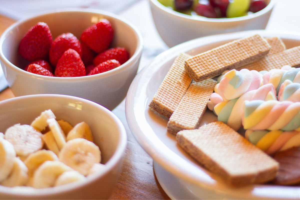 Bowls of strawberries, banana slices, and wafers, simple snack options for toddlers during travel.