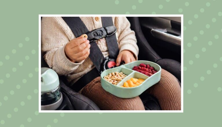 Toddler in a car seat eating a healthy snack from a divided container, showing easy and mess-free road trip snack ideas for kids.