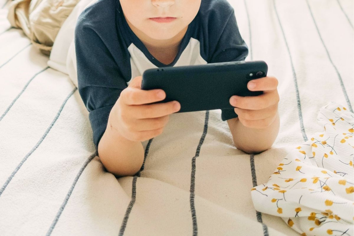 Child using a smartphone to learn money apps and basic financial skills.