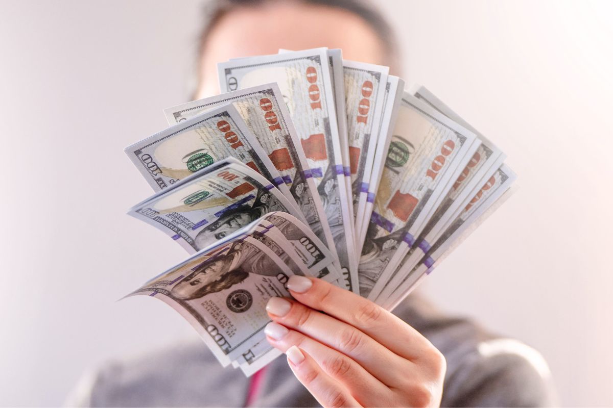 Holding dollar bills to represent saving and money awareness for beginners.