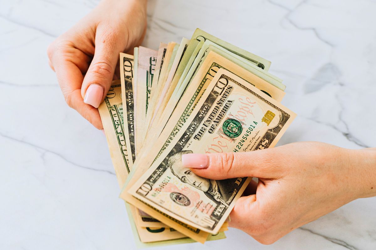 Hands counting cash to demonstrate real-life money handling and budgeting.